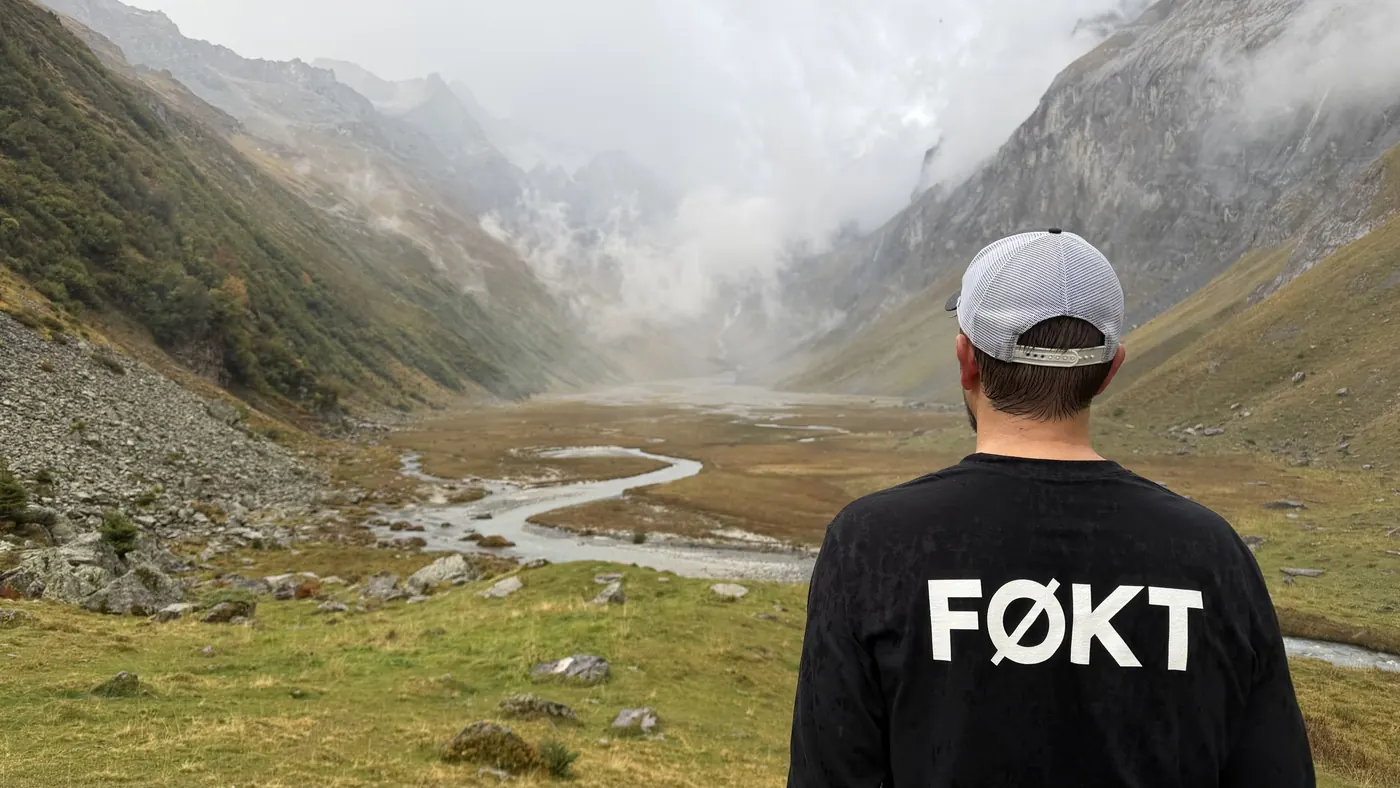 Person im FØKT-Shirt blickt in ein nebliges Bergtal